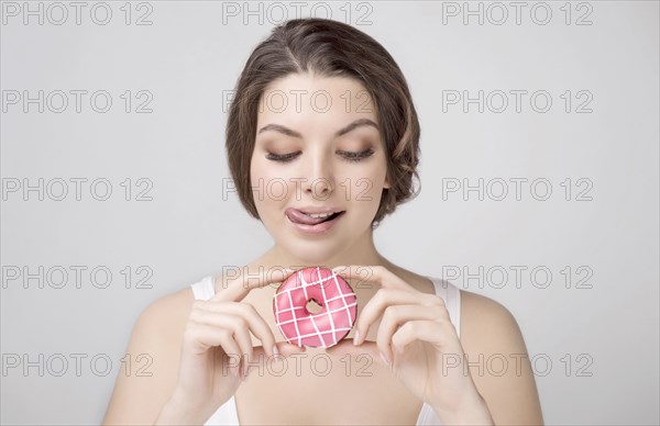 Caucasian woman holding donut and licking lips