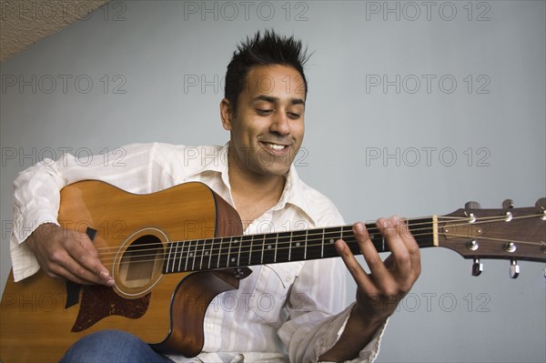 Mixed race man playing guitar