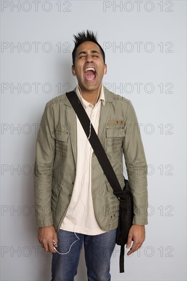 Shouting mixed race man wearing headphones and bag