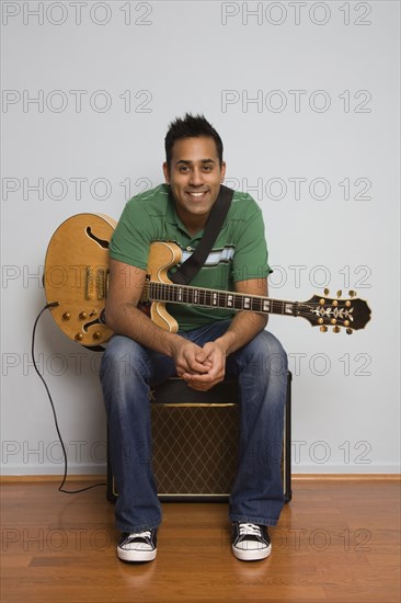 Mixed race man sitting with electric guitar