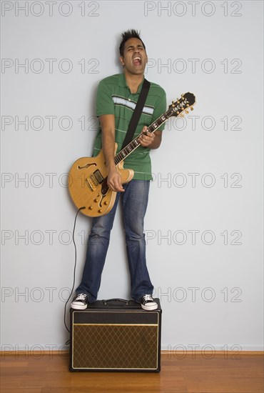 Mixed race man playing electric guitar