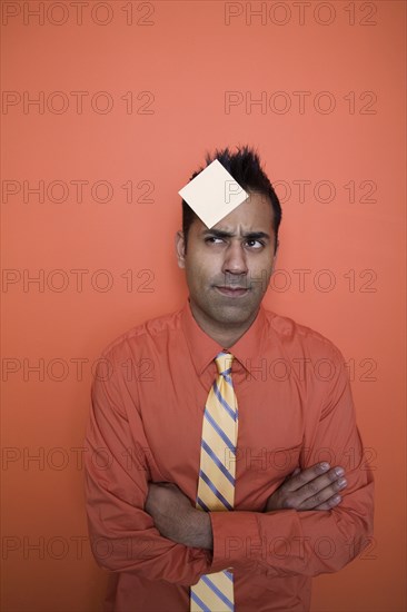 Mixed race businessman with sticky note on forehead