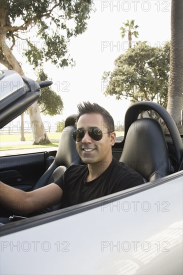 Mixed race man driving convertible
