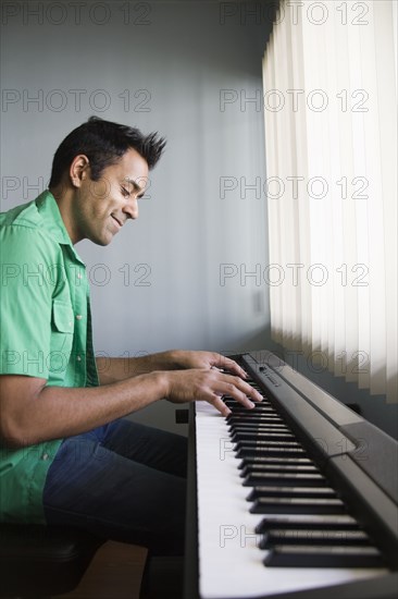 Mixed race man playing electric keyboard