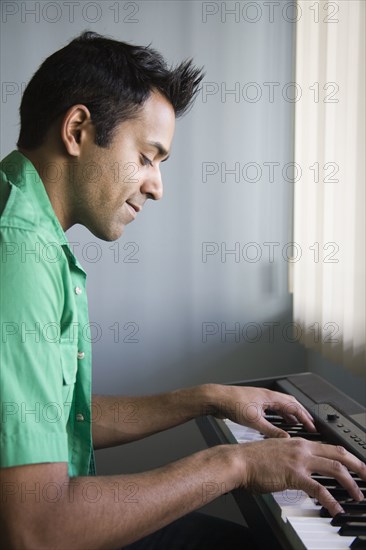 Mixed race man playing electric keyboard