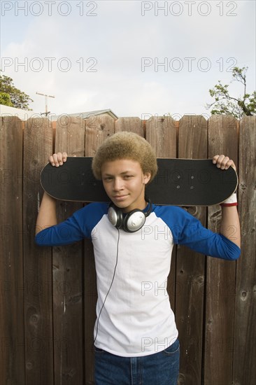 Mixed race boy in headphones holding skateboard