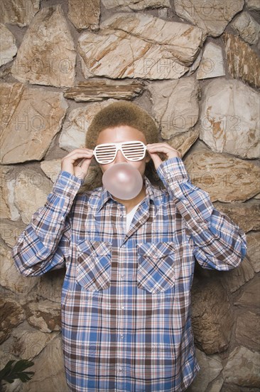 Mixed race boy in sunglasses chewing bubble gum