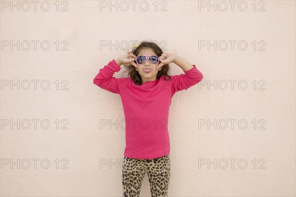 Hispanic girl wearing sunglasses and sticking out tongue