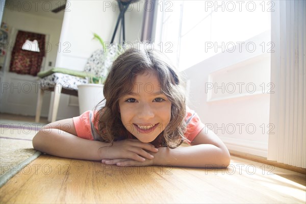 Smiling Hispanic girl laying on floor