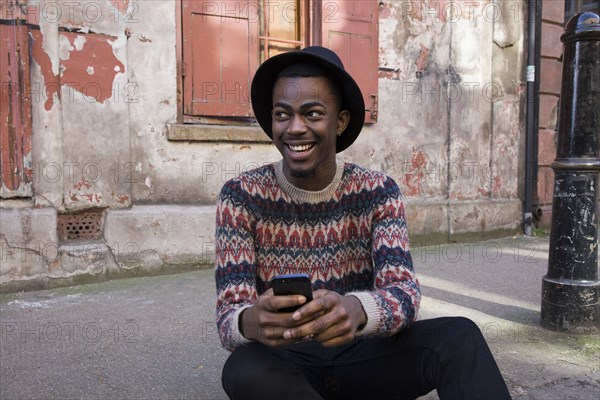 Black man using cell phone on urban sidewalk