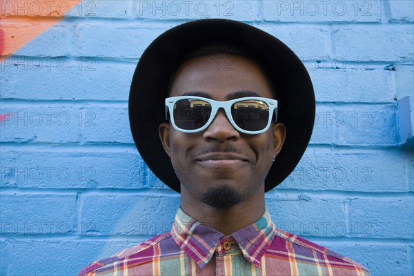 Black man wearing sunglasses near colorful wall