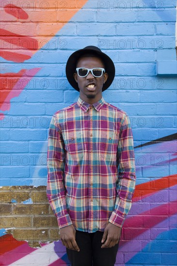 Black man wearing sunglasses near colorful wall