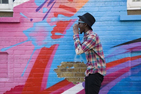 Black man in sunglasses shouting near colorful wall