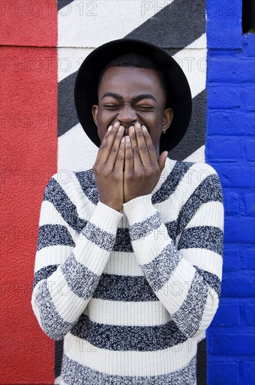 Black man laughing near colorful wall