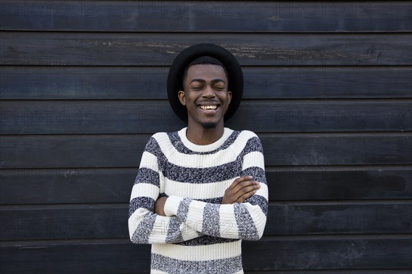 Black man laughing near wooden wall