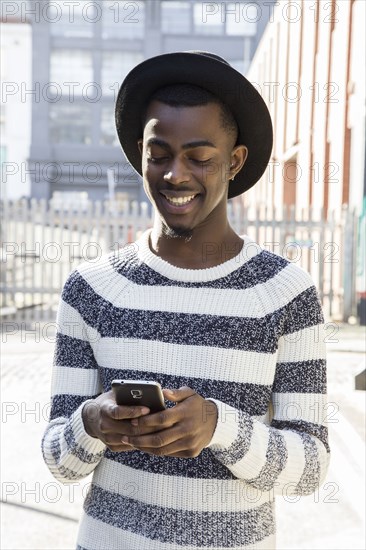 Black man using cell phone on urban sidewalk
