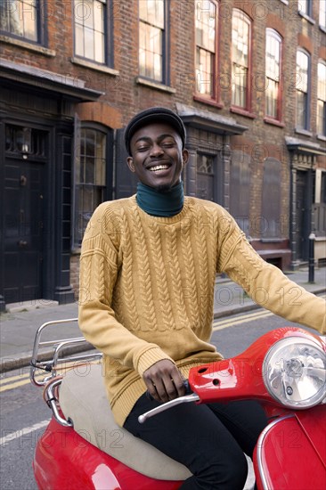 Black man riding scooter on urban street