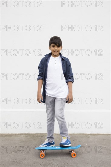 Asian boy standing on skateboard