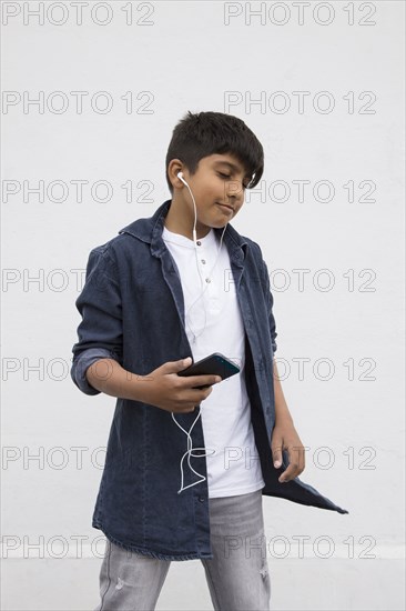 Asian boy listening to earbuds with cell phone