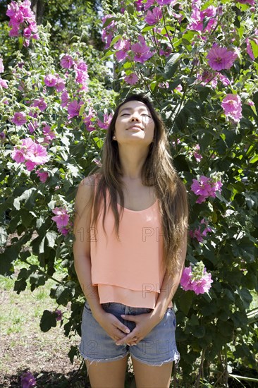 Asian woman standing under flowers