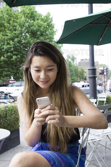 Asian woman using cell phone outdoors