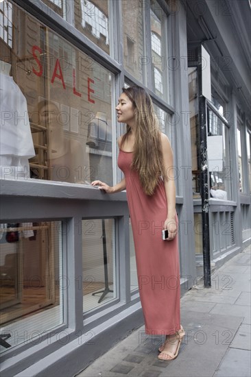 Asian woman window shopping outside store