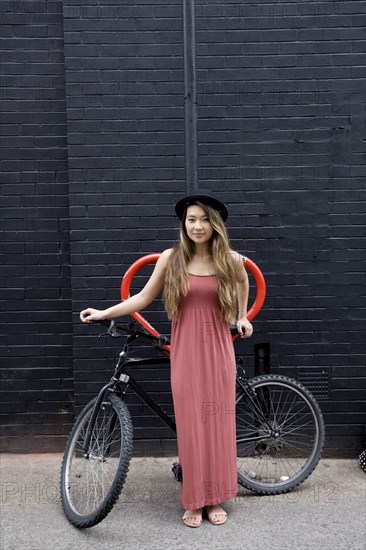 Asian woman standing with bicycle