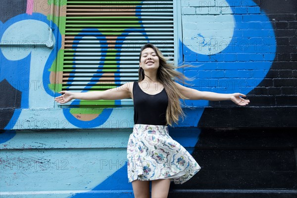 Asian woman cheering with arms outstretched