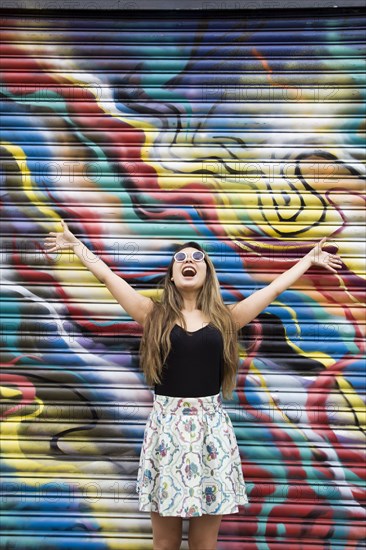 Asian woman cheering near graffiti wall