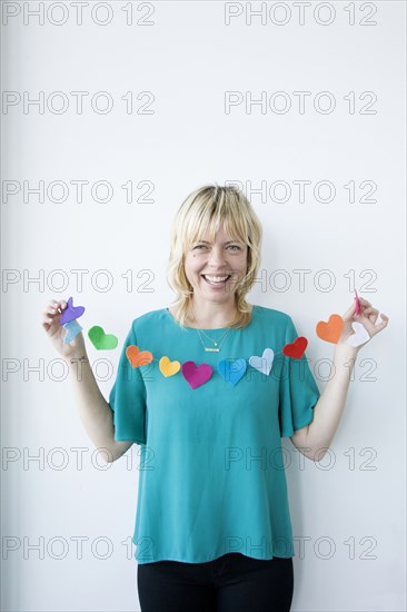 Caucasian woman holding string of paper hearts