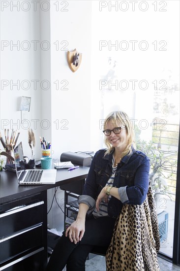 Caucasian woman posing at desk with laptop