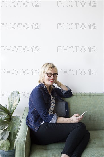 Caucasian woman sitting on sofa texting on cell phone