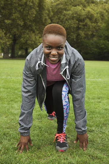 Black woman stretching legs in grass field