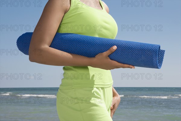 Hispanic woman holding yoga mat