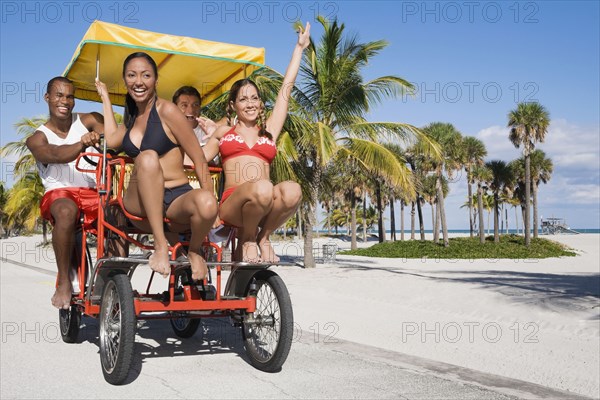 Multi-ethnic couples riding on pedal cart