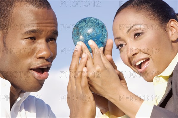 Multi-ethnic businesspeople looking at glass orb