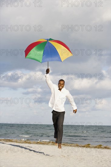 African man running with beach umbrella