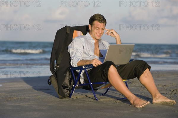 Hispanic businessman looking at laptop