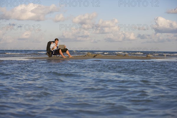 Hispanic businessman on sandbar