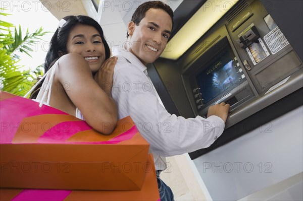 Hispanic couple using atm