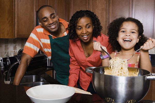 African parents watching daughter serve spaghetti