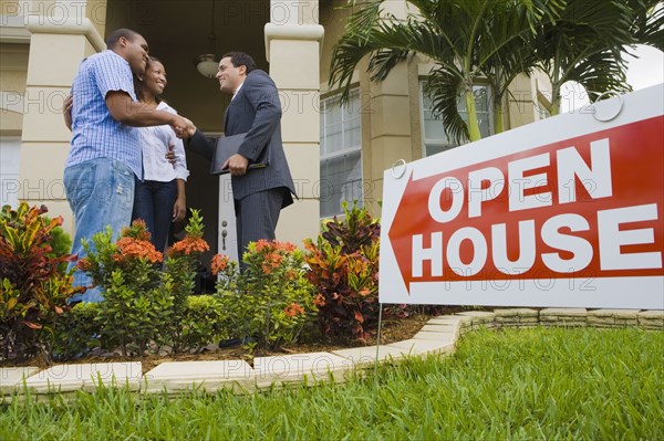 African couple shaking hands with Hispanic real estate agent