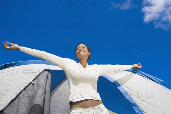 Hispanic woman stretching in front of tent