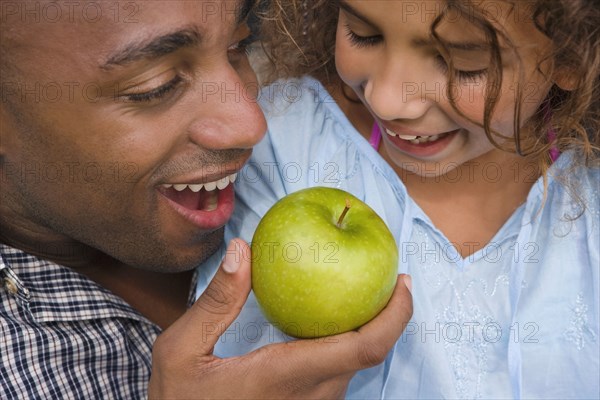 African father and daughter eating apple
