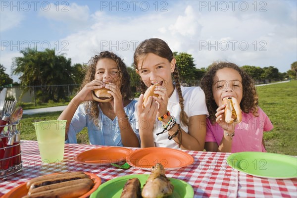 Hispanic girls eating at picnic table