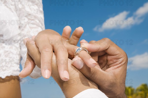 African groom putting ring on bride's finger