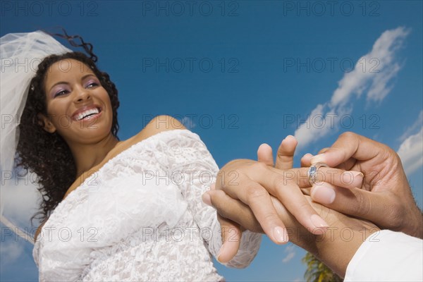 African groom putting ring on bride's finger