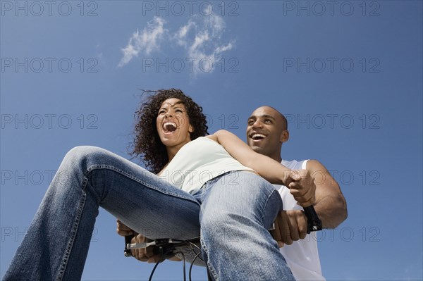 Multi-ethnic couple sitting on bicycle