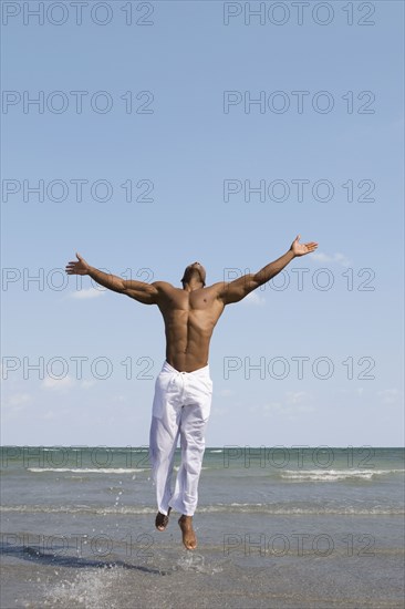 African man jumping in ocean surf