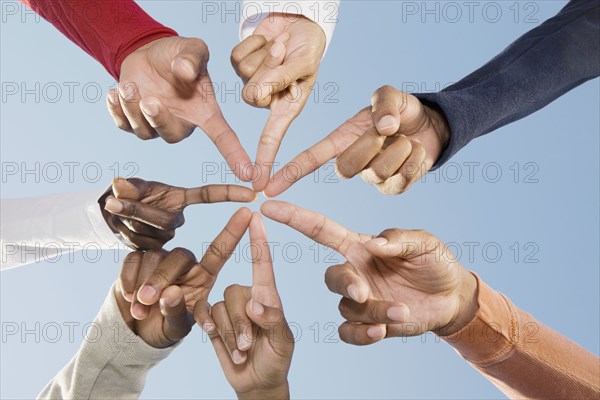 Multi-ethnic friends pointing fingers in circle